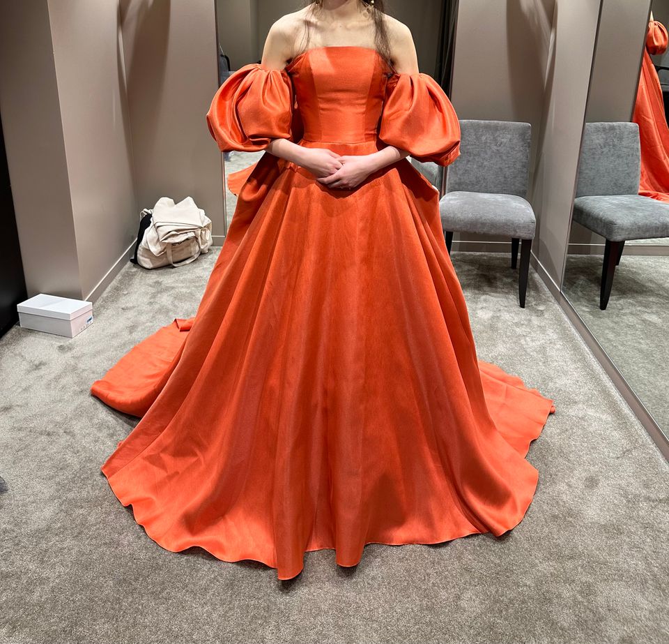 パフスリーブのオレンジドレス。サテンのツルツルした素材で角度